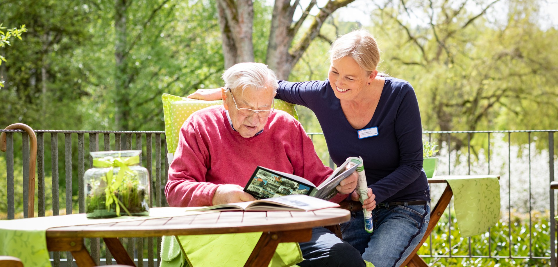 Frau Böhm, die gemeinsam mit einem Bewohner ein Buch durchstöbert.